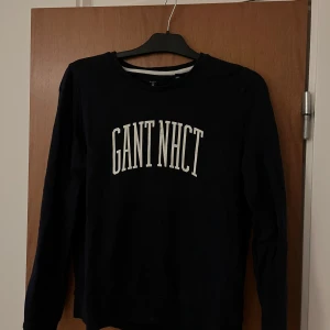 Marinblå sweatshirt från GANT - Säljer en marinblå sweatshirt från GANT. Själva tröjan är i bra skick men texten har spruckit lite i tvätten (se bild nummer 2). Pris går att diskutera