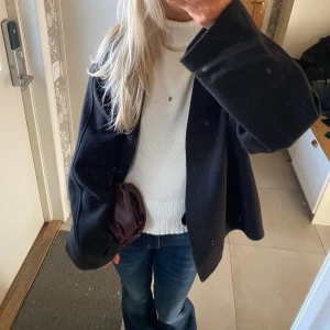 Figursydd polotröja - Jättefin figursydd polo med kabelstickat mönster på ärmarna. Lite vidare vid handlederna/ärmarna, ribbade detaljer vid tröjans slut över magen. Fint skick! 🤍