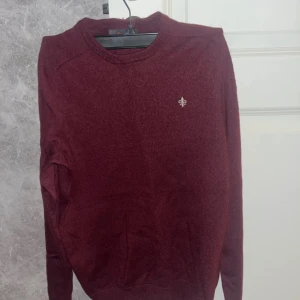 Vinröd tröja från Morris - Säljer en stilren vinröd tröja från Morris i 100% merinoull. Tröjan har en liten broderad detalj på bröstet och rund halsringning. Perfekt för kyligare dagar.