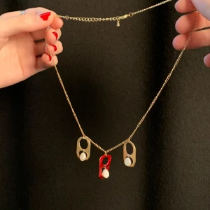 Guldigt halsband med pärlor - Ett fint enkelt handgjort halsband i guld med återvunna och renade burkflärpar i guld och röd smyckade med små pärlor. Halsbandet är i sin helhet ca 45 cm.
