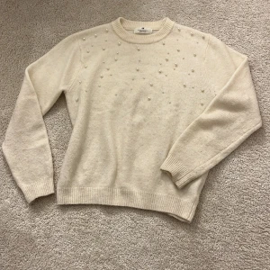 Vit tröja med pärlor från H&M - Vit tröja från H&M dekorerad med pärlor på framsidan. Storlek 158-164 som motsvarar XS. Kräm vit färg.