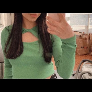 Grön ribbad topp från Glamorous - Snygg grön ribbad topp från Glamorous med unik twistdetalj och utskärning framtill. Perfekt för att ge din outfit en cool touch. Långärmad och croppad design som passar perfekt till både jeans och kjol.