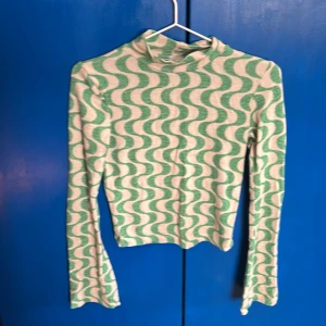 Grön och vit mönstrad topp från Stradivarius - Säljer en snygg och groovy grön och vit topp från Stradivarius med ett vågigt mönster. Toppen har långa ärmar och en hög hals. Älskar denna och haft den länge men inte min stil längre. Jätte bekväm och schysst mönster💘