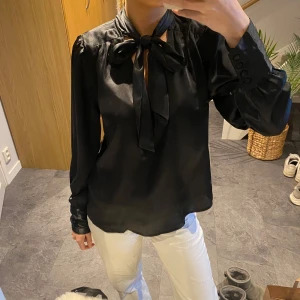 Svart blus med knytning vid hals - Säljer denna supersnygga svarta blus med knytning vid halsen från CC Capri collection!