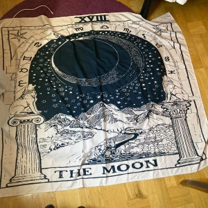 The Moon, dekorativt tyg - Dekorativt tyg av tarotkortet 'The Moon', med stjärnor, måne, berg och astrologiska symboler. Perfekt för dig som gillar magi, symbolik och unika illustrationer. Uppskattningsvis 150 x 150 cm men har ej exakta mått. Polyester tyg.