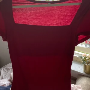 Vinröd kortklänning med fyrkantig hals - Säljer en stilren vinröd kortklänning med fyrkantig halsringning och korta ärmar. Klänningen har en enkel och clean design som ger en snygg siluett. Perfekt för dig som gillar minimalistisk stil och vill ha en klänning som sticker ut med sin färg.