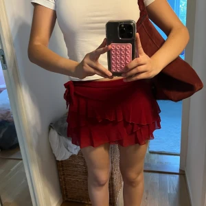 Röd volangkjol med knyt i sidan - Supersöt röd kortkjol med flera lager volanger och knyt i sidan. Materialet är tunt och ger en snygg rörelse när du går. Storlek M använd bara en gång köpt på shein ❤️ jätte mjuk material och har även shorts under 😌