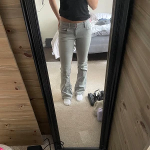 Ljusgrå bootcut jeans - Säljer ett par ljusgrå jeans med bootcut passform och klassiska fem fickor. Dom är lågmidjade och raka ben som blir lite vidare nedtill. Materialet är mjukt och stretchigt. Kommer från young gina tricot och är i storlek 164, (passar mig som har S)
