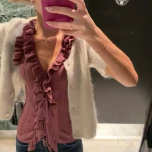  volangtopp med knyt🩷 - Supersöt lila topp med djup v-ringning och volangdetaljer längs hela kanten. Toppen är ribbad och har knyt framtill för extra snygg passform. Perfekt att styla med jeans eller kjol för en trendig look. Passar S också 