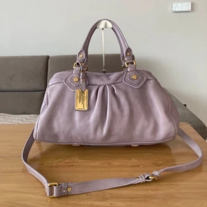 Ljuslila handväska Marc by Marc Jacobs - Superfin ljuslila handväska från Marc by Marc Jacobs i mjukt skinn. Väskan har både handtag och justerbar axelrem