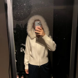 Vit teddyjacka med fuskpälsluva - Supermysig vit teddyjacka med fluffig fuskpäls runt luvan. Jackan har dragkedja framtill, ribbade muddar och midja. Säljer pga ingen användning. Saknar märke och storlek men uppskattar storlek XS/S Köpt på Vinted för 600 