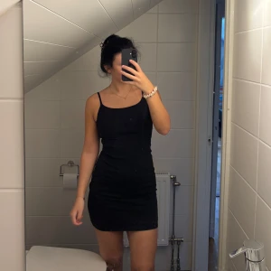 Tight miniklänning med öppen rygg, Bik Bok - Säljer en svart kort klänning med smala axelband och öppen rygg. Klänningen har en tight och stretchig passform som känns jätteskön mot huden, (använd endast ett fåtal gånger). 