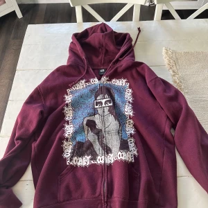 Vinröd OBEY hoodie med tryck, stl L - Säljer en vinröd hoodie från OBEY i storlek L. Tröjan har dragkedja, huva med snörning och en stor grafisk print framtill i blått, vitt och svart. Mjuk insida och känguruficka. Perfekt för dig som gillar streetwear och vill sticka ut.