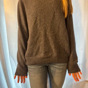 Mörkgrå stickad tröja med loose fit - Mysig mörkgrå stickad tröja med avslappnad passform och långa ärmar. Tröjan har ribbade muddar vid ärmslut och nederkant. Enkel och stilren design som funkar till jeans eller kjol.