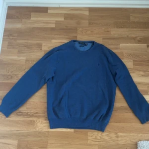 Blå tröja från Polo Ralph Lauren - Snygg blå tröja från Polo Ralph Lauren i mjuk pima bomull. Klassisk rund hals och diskret logga broderad på bröstet. Tröjan har långärmade och ribbade muddar vid ärmslut och nederkant. Perfekt för dig som gillar stilrena och bekväma plagg.