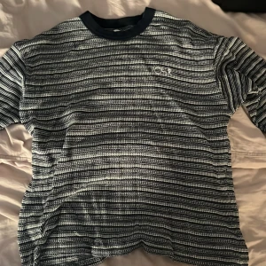 Randig tröja från Polar Skate Co - Säljer en svartvit randig tröja från Polar Skate Co i storlek L. Tröjan har ett broderat Polar Skate Co-logo på bröstet och en ribbad mörkblå krage. Materialet är mjuk bomull och passformen är normal med långärmade ärmar. Perfekt för dig som gillar streetwear och snygga detaljer.