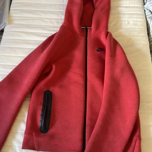 Röd Nike tech fleece - Säljer en Nike tech fleece som har använts ett par gånger. Den är i jättebra skick och har inga fel pris kan diskuteras.