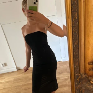 Svart axelbandslös långklänning från Shein - Säljer en svart klänning utan band från SHEIN, klänningen har en slits där bak och ett väldigt elastisk material. Klänningen är helt ny och jag har aldrig använt den ute. Klänningen är i storleken 13y, men den passar mig och jag har storleken XS.  Skriv för frågor!
