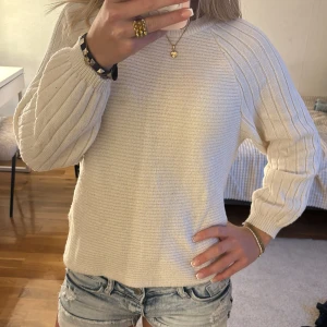 Beige stickad tröja med ribbade ärmar - Säljer en beige stickad tröja med rund hals och breda, ribbade långärmar. Tröjan har en loose passform. Materialet är mjukt och skönt, och färgen är ljusbeige som passar till allt. Storlek Xs men är lite mer som S!