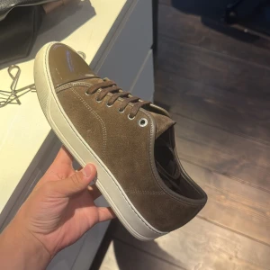 Bruna mockasneakers med lackad tå UK6! - Snygga sneakers från Lanvin i brun mocka med matchande bruna snören och vit sula. Tån är i blankt brunt lack som ger en cool kontrast till mockan. Perfekta för dig som gillar stilrena men unika detaljer på dina skor. Helt nya snören med följer skorna k väldigt bra skick 8/10 box finns! Skickas endast med vi rätt pris och skriv om ni vill ha med så kan vi bestämma till rätt pris 