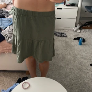 Grön volangkjol från Young Original - Säljer en grön kjol från Young Original i storlek 14. Kjolen har en volangdetalj och resår i midjan för skön passform. Den är A-linjeformad och slutar strax ovanför knäna, perfekt för dig som gillar enkel och chill stil. Endast använt en gång