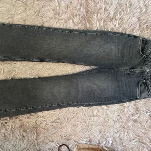 Grå raka jeans - Säljer ett par grå jeans med rak passform och klassisk femficksdesign. Jeansen har en snygg tvättad look och är perfekta för en avslappnad stil. 