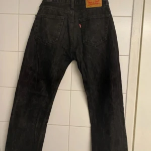 Levi's 505 svarta jeans straight fit - Svarta Levi's 505 jeans med klassisk straight fit. Jeansen har fem fickor, dragkedja och den ikoniska läderpatchen bak. Snygg tvättad svart färg som passar till allt. Perfekta för dig som gillar en tidlös och avslappnad look.