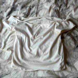 Vit offshoulder topp från H&M - Säljer en enkel och stilren vit offshoulder topp från H&M. Toppen har korta ärmar och är gjord i mjuk bomull, perfekt för en avslappnad look. Passar dig som gillar minimalistisk stil och vill ha något bekvämt och snyggt. OBS liten bus fläck vid ena ärmen går o få bort.