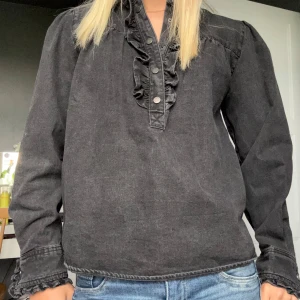 Neo nior blus - En jättefin mörkgrå jeans blus från Neo Nior som aldrig har använts. Volanger vid både ärmar och hals och knappar ned från halsen. Nypris 800-900kr🩷