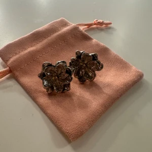 Silvriga blommiga örhängen - Säljer ett par chunky silvriga örhängen i form av stora blommor. De har en cool, glansig finish och är perfekta för dig som vill sticka ut med ett statement-smycke. 