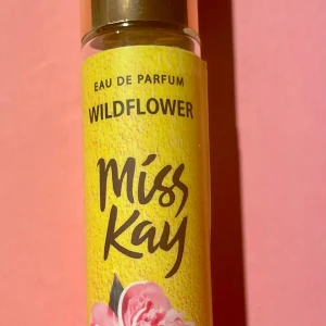 Miss Kay Wildflower Eau de Parfum 25 ml  - Ca 40% kvar (se bilder) Fräsch och blommig Eau de Parfum från Miss Kay med namnet Wildflower. Flaskan är smal och gjord av glas med en gul etikett och rosa blomdetaljer. Parfymen är vegansk och tillverkad i Italien. Perfekt för dig som gillar lätta, blommiga dofter.