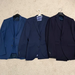 Tre klassiska blå/navy/dark navy kostymkavajer - Dags att sälja tre av mina kostymer [suit and trousers] som inte längre passar mig. i olika blå nyanser från vänster blå, mitten navy och höger dark navy, Har använt alla 3 inte mer än 2-3 gånger var så de är i perfekt skick ovh som ny. Alla  Perfekt för dig som vill ha en snygg och tidlös look., första från vänster storlek 44 köpt utomlands, två andra åt höger storlek 46 som köpt från Brothers Borås - Riley märke, flera bilder kan skickas. 680kr/st