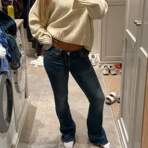 True Religion Joey Low Rise Flare jeans - Säljer ett par blå True Religion Joey jeans med låg midja och utsvängda ben. Snygga kontrastsömmar och ikoniska fickdetaljer bak med lock och knapp. Storlek 26, oanvända. Nypris 1300 kr. 