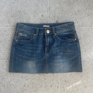 Blå jeanskjol från ELDYS - Snygg blå jeanskjol från ELDYS med klassisk femficksdesign, knapp och dragkedja framtill samt bälteshällor. Kjolen är kort och har en rak passform som ger en cool och avslappnad vibe. Perfekt för dig som gillar denim och vill ha en enkel men trendig look. Midjemått: 35cm. Säljer fler kjolar på mitt konto. Användgärna köp nueller kom med prisförslag❤️