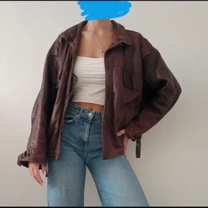 Brun oversized skinnjacka  - Säljer en brun oversized skinnjacka med coola detaljer som bälte i midjan och stora fickor framtill. Jackan har klassisk krage, knappar och långa ärmar. Perfekt för dig som gillar vintagevibbar och vill ha en unik look. Vintage brun läder jacka, oversized för hösten.  Normala tecken på användning samt lädret - veck m.m.  Totallängd ca 65 cm  Passar M/L  För fler exakta mått eller bilder skicka ett meddelande.
