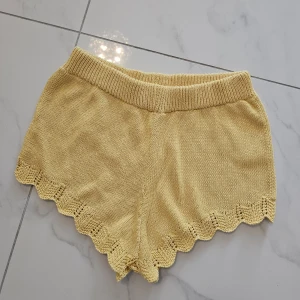 Gula stickade shorts med volangkant - Snygga ljusgula stickade shorts med bred resår i midjan och dekorativ volangkant längst ner. Perfekta för sommarens chill dagar, mjuka och sköna med en loose passform. Tillverkade i Turkiet, storlek M.