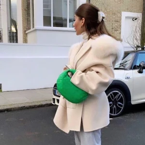 Krämvit kappa med pälsdetalj - Säljer en beige kappa med breda axlar och lyxig vit päls runt kragen. Jackan har en oversized passform och långa ärmar, perfekt för att ge en cool och elegant vibe. Stängs framtill och har stilrena linjer som gör den extra trendig.anvönt den några få gånger men den är som ny. Den är lowkey onesize jag tror 