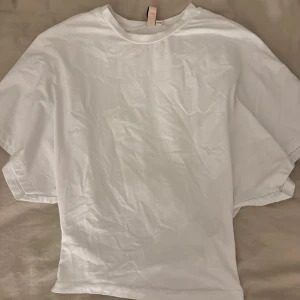Vit T-shirt från Nelly  - Vit T-Shirt från Nelly som är tajt i magen och lite pösigare i ärmarna. Superfin och i bra skick. Storlek XXS