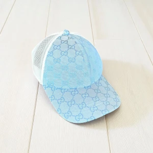 Blå Gucci keps med mesh och logomönster - Snygg keps från Gucci i ljusblått med klassiskt GG-logomönster över hela framsidan. Baksidan är vit mesh för extra ventilation och har justerbar rem. Perfekt för dig som vill ha en lyxig och trendig accessoar med streetkänsla.