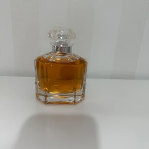 Mon Guerlain Eau de Toilette 100ml - Mon Guerlain Eau de Toilette i en lyxig, transparent glasflaska med silverdetalj och tydlig, geometrisk form. Innehåller 100 ml av den ikoniska doften med bärnstensfärgad vätska. Perfekt för dig som gillar exklusiva och klassiska parfymer. Köpte från sephora 