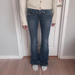 Blå lågmidjade bootcut jeans från Diesel - Snygga blå jeans från Diesel med klassisk bootcut-passform och låg midja. Jeansen har fyra fickor, tydliga sömmar och en liten Diesel Industry-logga vid myntfickan. Materialet är slitstarkt denim i bomull och de har en cool, något tvättad look. Är något skadade vid nederkanten av jeansen men det går lätt att sy/klippa bort då jeansen är väldigt långa! Priset kan diskuteras 