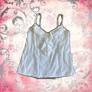 Vit linnetopp med volang från Atmosphere - Söt vit linnetopp från Atmosphere gjord i 100% bomull. Storlek 40 men passar mig som bär s bra.Toppen har smala axelband som är justerbara, v-ringad hals och snygg volangdetalj framtill. Perfekt för varma dagar när man vill vara lite extra fin. Rekommenderar att ha vita kläder under då man kan se igenom i vissa ljus. Har tyvärr ingen koll på orginalpriset. (Pris kan diskuteras)