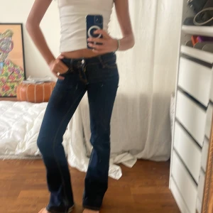 Weekday mörkblå bootcut jeans - Weekday cheap monday  jeans i mörkblå tvätt med klassiska kontrastsömmar och låg midja. Modellen har bootcut-ben som ger en schysst siluett och fem fickor. Jeansen är gjorda i slitstarkt denim och har dragkedja och knapp framtill.