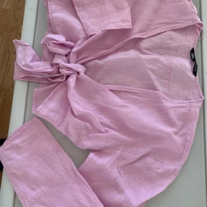 Ljusrosa omlottblus från Zara - Säljer en ljusrosa omlottblus från Zara använt max 2 ggr i luftig linnemix. Blusen har långa ärmar och knyt framtill för en chill och trendig look. Perfekt att styla med jeans eller kjol för en fräsch vibe. Färgen är superfin och materialet känns lätt mot huden.