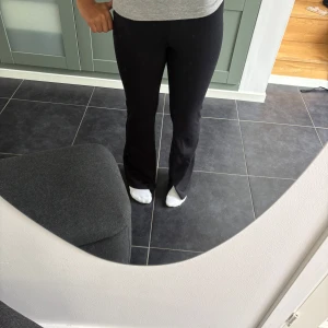 Svarta bootcut mjukisbyxor/träningsbyxor. - Svarta mjukisbyxor med bootcut-snitt och stretchigt material som sitter skönt och följer kroppen. Byxorna är high waist och  har en enkel design utan synliga detaljer och är perfekta för en chill och avslappnad stil. Materialet känns mjukt och följsamt, och midjan är normal.