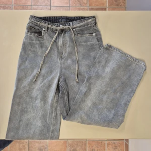 Grå/beige jeans med snörning - Snygga grå/beige baggy jeans från H&M. Modellen har en loose passform och raka ben, med snörning i midjan. Stl 34, men jag kunde ha dem som stl 36 då jag använde de som högmidjade✨️