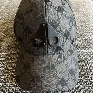 Svart keps från Moose Knuckles - Snygg svart keps från Moose Knuckles med unikt mönster av kedjor och loggor över hela kepsen. Framtill sitter två svarta metalldetaljer som ger en cool edge. Kepsen är tillverkad i 100% polyester och har justerbar rem bak för perfekt passform.