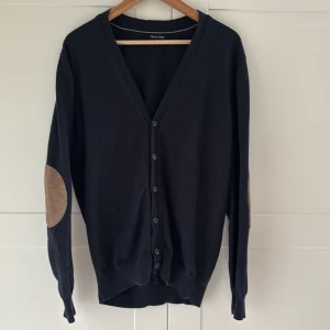Mörkblå kofta från Massimo Dutti  - Säljer denna snygga mörkblå kofta från Massimo Dutti med mocka-patchar på armbågarna. Materialet är bomull - Kashmir blandning. Storleken på tröjan är M. Vid frågor eller funderingar så är det bara höra av sig! 