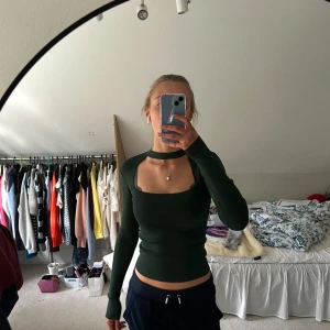 Mörkgrön ribbad topp från Zara - Snygg mörkgrön ribbad topp från Zara med lång ärm och cut-out detalj vid halsen. Perfekt att styla med jeans, shorts eller kjol! 🪐❣️