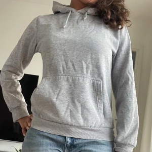 Grå hoodie med huva - En stilren, lite tajtare grå hoodie med huva och snörning.